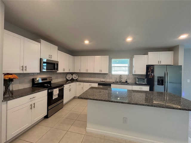 kitchen featuring a kitchen island, backsplash, appliances with stainless steel finishes, and white cabinetry