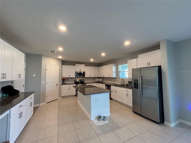 kitchen with visible vents, a kitchen island, appliances with stainless steel finishes, white cabinets, and decorative backsplash