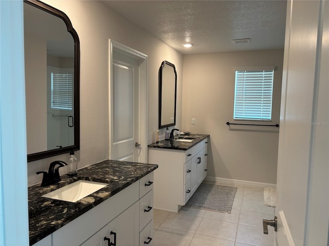 bathroom with tile patterned floors, visible vents, a textured ceiling, and a sink