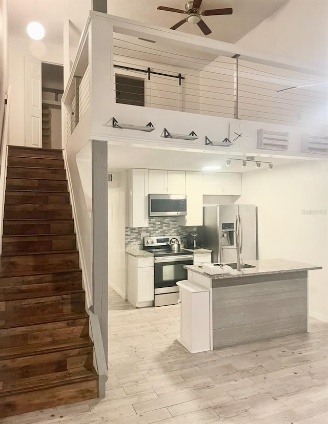 kitchen with stainless steel appliances, light wood finished floors, a ceiling fan, and decorative backsplash