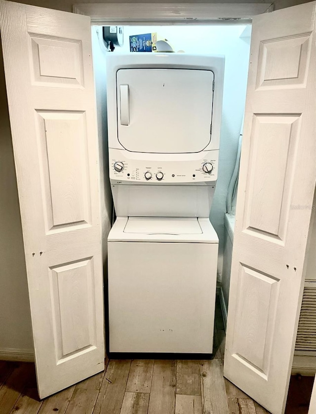 washroom featuring laundry area, stacked washer and clothes dryer, and light wood-style floors