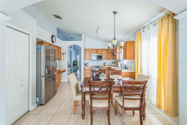 dining area with lofted ceiling, light tile patterned floors, sink, and a notable chandelier