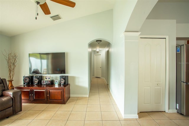 living room with ceiling fan, vaulted ceiling, and light tile patterned flooring