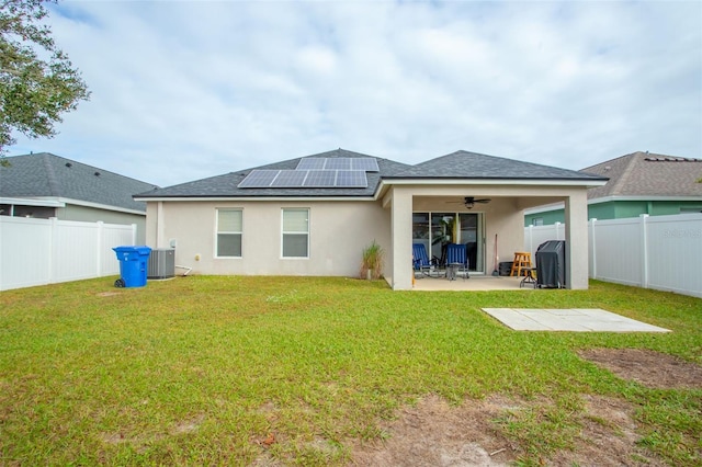 back of house featuring a lawn, ceiling fan, solar panels, and a patio