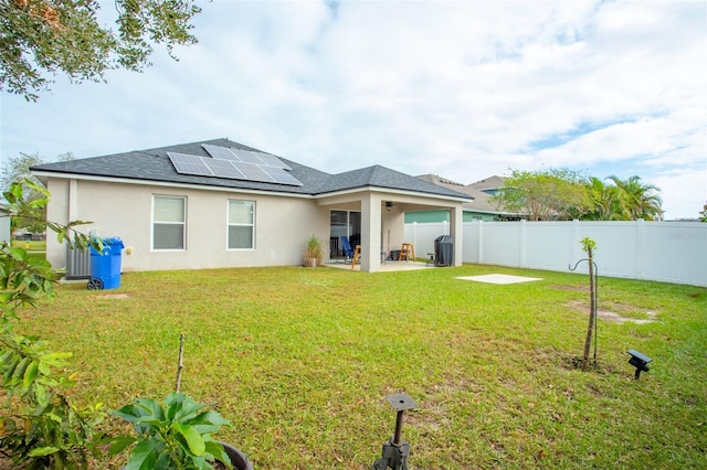 rear view of property featuring a patio, solar panels, and a lawn