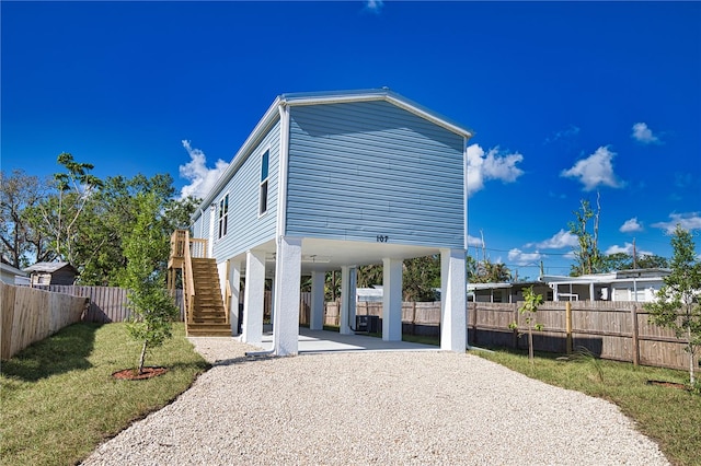 back of property with a lawn and a carport