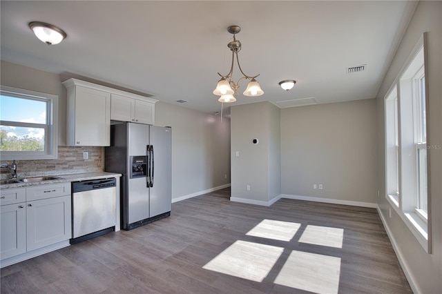 kitchen with light hardwood / wood-style floors, stainless steel appliances, decorative backsplash, sink, and white cabinetry