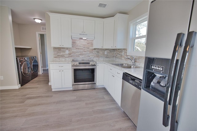 kitchen with white cabinetry, decorative backsplash, appliances with stainless steel finishes, and washer and dryer