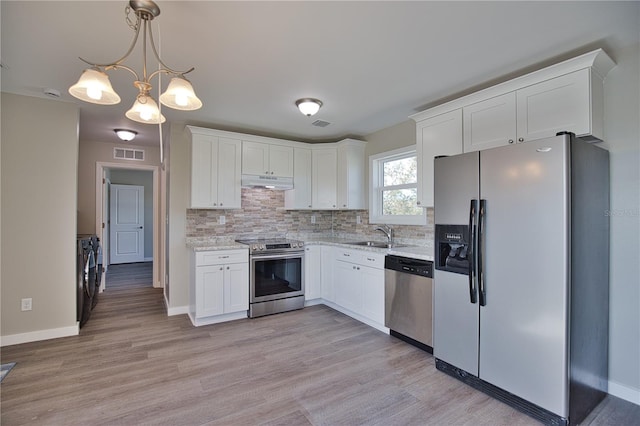 kitchen featuring separate washer and dryer, stainless steel appliances, pendant lighting, white cabinetry, and light wood-type flooring