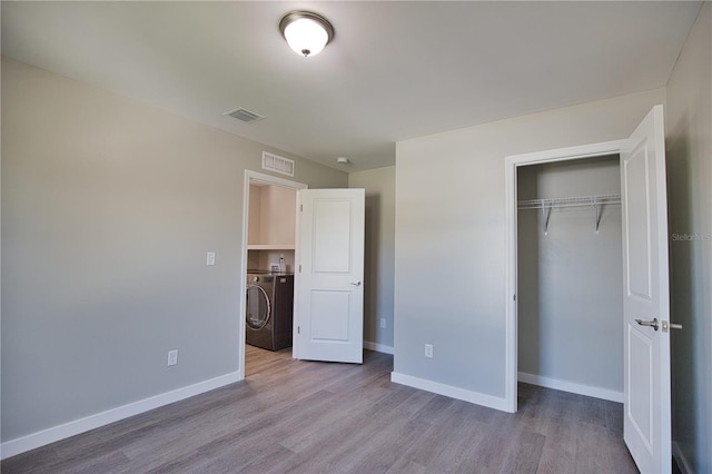 unfurnished bedroom with a closet, light hardwood / wood-style flooring, and washer and clothes dryer