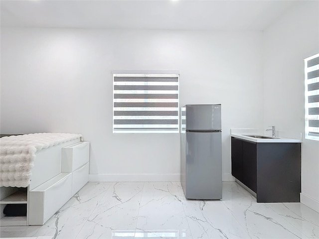 interior space featuring multiple windows, stainless steel fridge, and sink