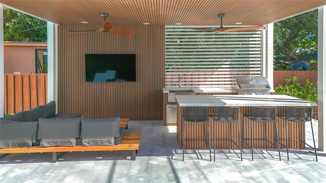 view of patio featuring ceiling fan, exterior bar, and grilling area