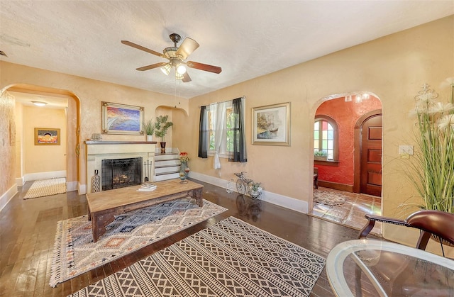 living room featuring ceiling fan, wood-type flooring, and a textured ceiling