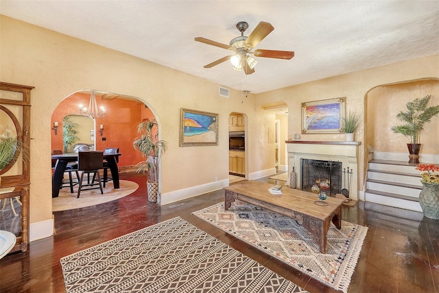 living room with ceiling fan with notable chandelier and dark hardwood / wood-style floors