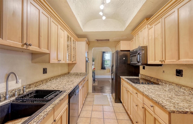 kitchen featuring light stone counters, a textured ceiling, sink, black appliances, and light tile patterned floors