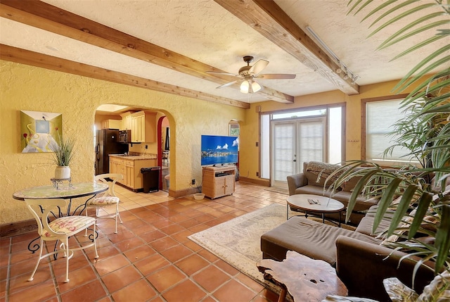 tiled living room featuring french doors, beam ceiling, a textured ceiling, and ceiling fan