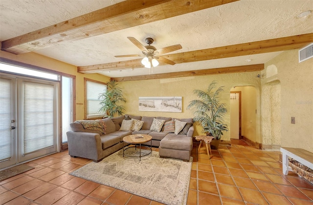 living room featuring beam ceiling, ceiling fan, tile patterned flooring, and a textured ceiling