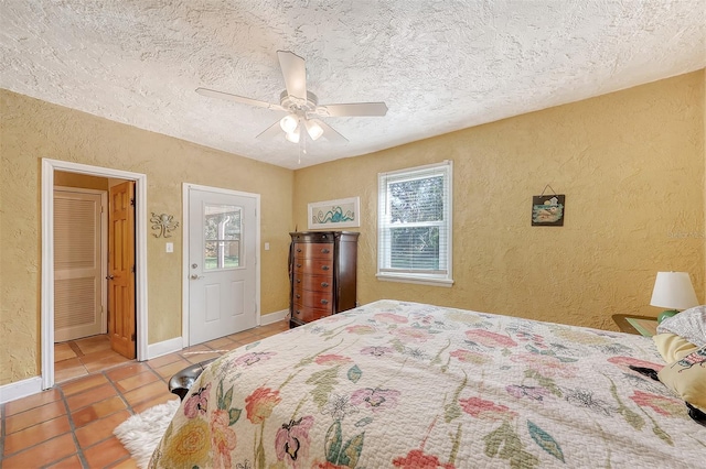 bedroom with light tile patterned floors, a textured ceiling, multiple windows, and ceiling fan