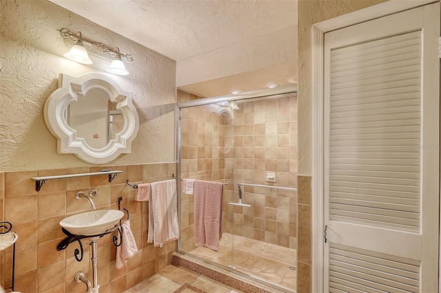 bathroom featuring tile patterned flooring, sink, a shower with shower door, and a textured ceiling