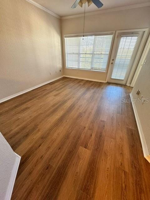 unfurnished room featuring dark hardwood / wood-style flooring, crown molding, ceiling fan, and a healthy amount of sunlight