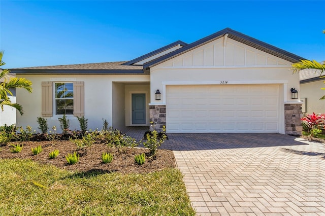 ranch-style house featuring stone siding, stucco siding, an attached garage, and decorative driveway