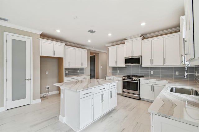 kitchen featuring white cabinetry, sink, a kitchen island, and appliances with stainless steel finishes