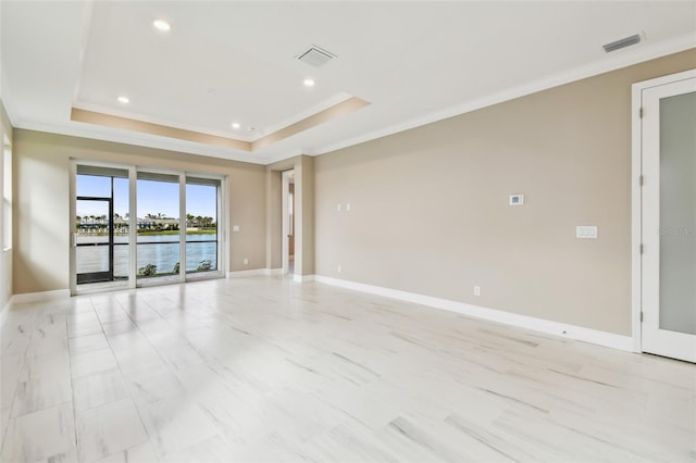 empty room with a water view, a raised ceiling, and crown molding