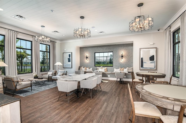 dining room with dark hardwood / wood-style floors, crown molding, brick wall, and an inviting chandelier