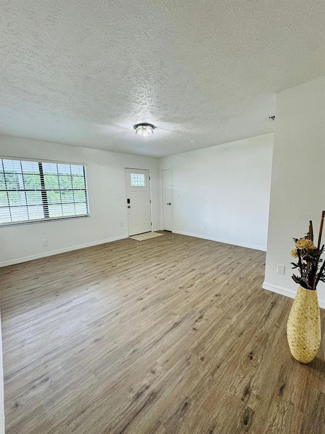 empty room with light hardwood / wood-style flooring and a textured ceiling