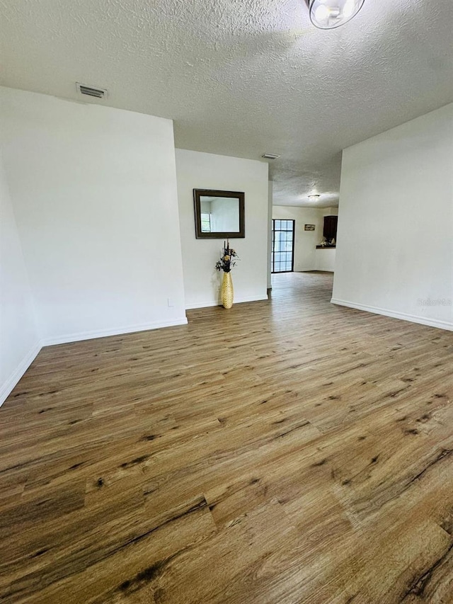 unfurnished living room featuring wood-type flooring and a textured ceiling