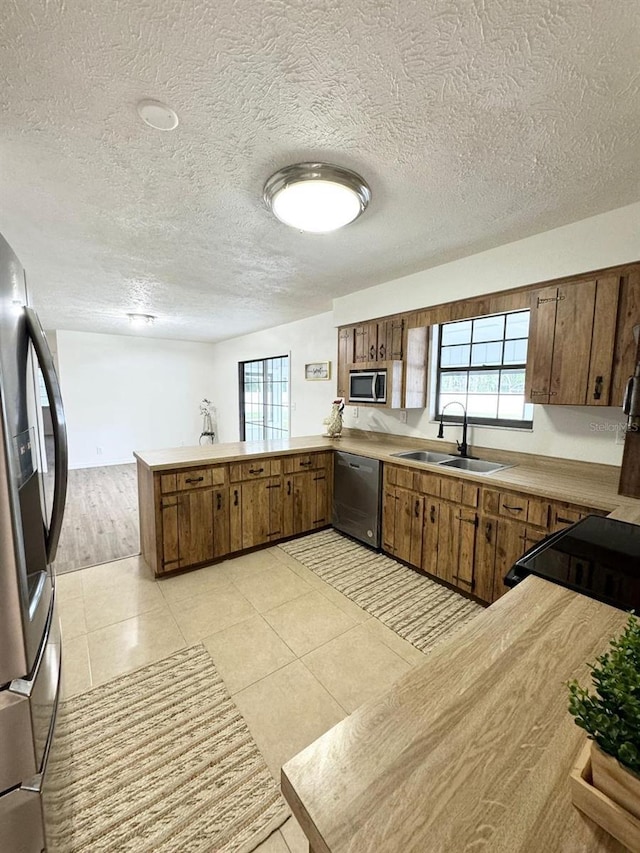 kitchen featuring kitchen peninsula, sink, a textured ceiling, and appliances with stainless steel finishes