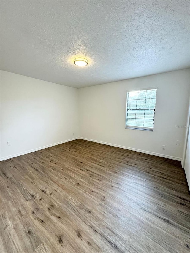 spare room featuring wood-type flooring and a textured ceiling