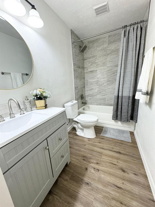 full bathroom with shower / bath combo, hardwood / wood-style floors, a textured ceiling, toilet, and vanity