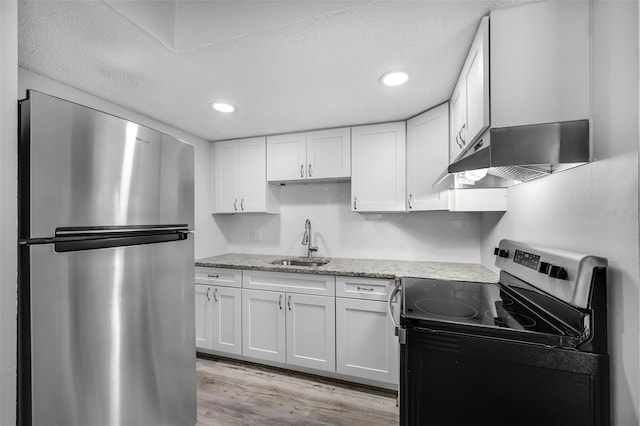 kitchen with exhaust hood, sink, light hardwood / wood-style flooring, appliances with stainless steel finishes, and white cabinetry