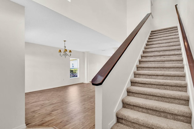 staircase with hardwood / wood-style floors and an inviting chandelier