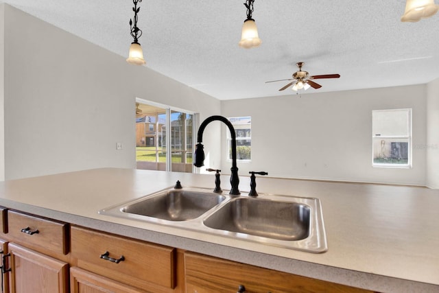 kitchen featuring pendant lighting, a textured ceiling, ceiling fan, and sink