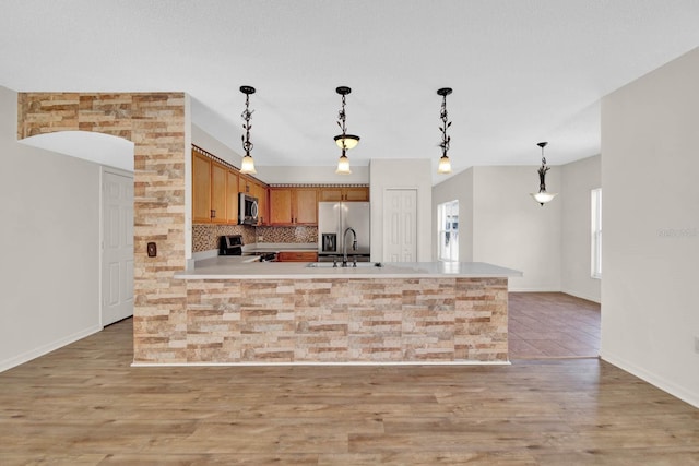 kitchen with pendant lighting, sink, stainless steel appliances, and light hardwood / wood-style flooring