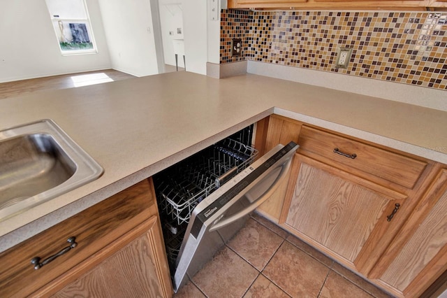 kitchen featuring dishwasher, sink, light tile patterned floors, and backsplash