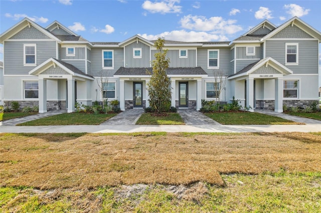 view of property with a front yard, stone siding, and a residential view