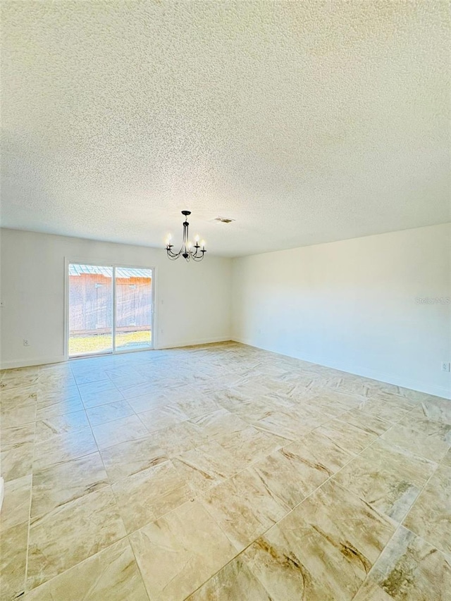 empty room featuring a textured ceiling and an inviting chandelier