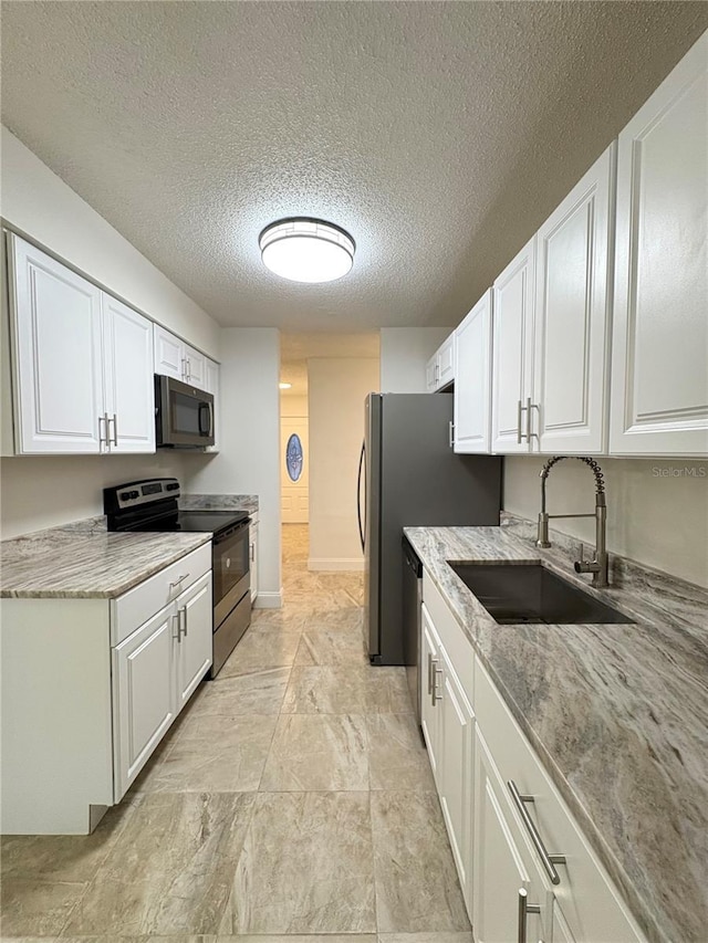 kitchen with a textured ceiling, white cabinetry, sink, and appliances with stainless steel finishes