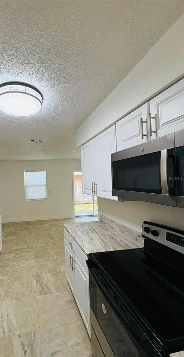 kitchen with white cabinetry, stainless steel appliances, and a textured ceiling