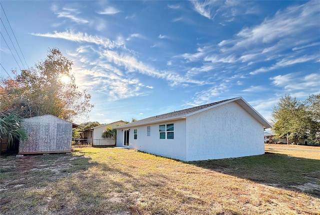 rear view of house with a storage shed and a yard