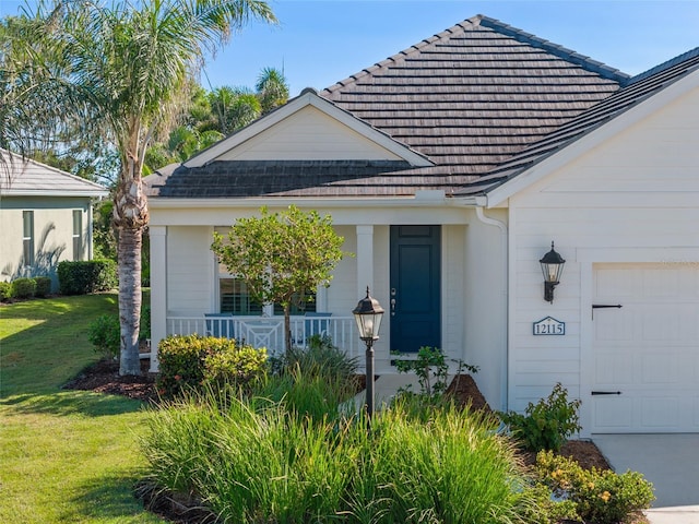 property entrance with covered porch, a garage, and a lawn