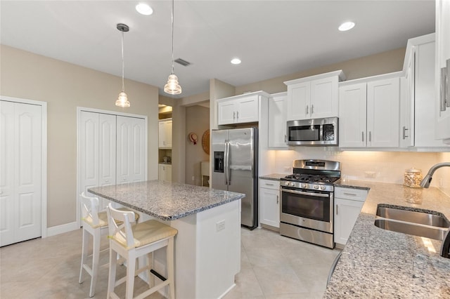 kitchen featuring appliances with stainless steel finishes, backsplash, sink, pendant lighting, and white cabinetry