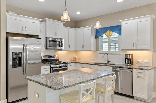 kitchen featuring white cabinets, appliances with stainless steel finishes, hanging light fixtures, and sink