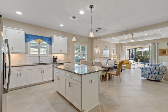 kitchen featuring ceiling fan, sink, a center island, pendant lighting, and dark stone counters