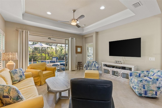 living room featuring a tray ceiling and light tile patterned flooring