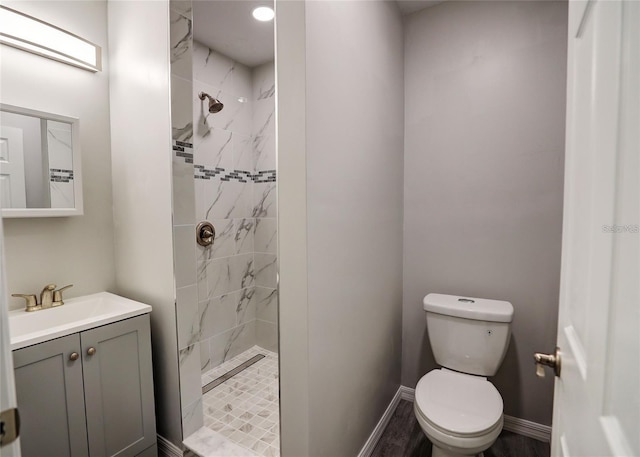 bathroom with tiled shower, vanity, hardwood / wood-style flooring, and toilet