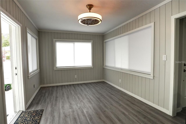 interior space with dark hardwood / wood-style flooring, wooden walls, and ornamental molding